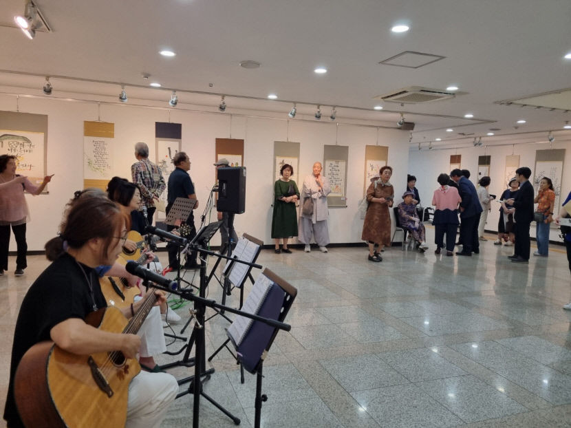 이동자씨의 작품나눔전 전시장을 찾은 관람객들이 기타동아리 '지이락'의 연주를 들으며 작품을 감상하고 있다.