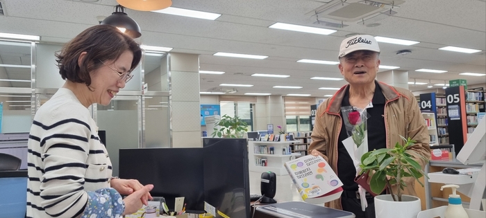 지난 23일 경북도교육청정보센터에서 범진열씨가 대출받은 책과 함께 장미꽃을 선물받은 뒤 즐거워하고 있다. 천윤자시민기자