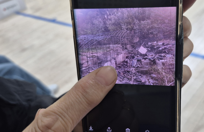 산불로 폐허가 된 김용복씨의 밭 모습을 담은 사진을 김 씨의 며느리가 휴대전화로 보여주고 있다. 이 사진은 김 씨의 큰아들이 촬영했다. 조윤화 기자