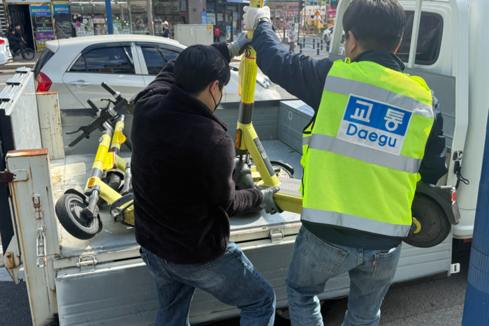 15일 대구 동구 율화광장 인근 보행도로에 무단 방치된 공유형 PM 을 단속원이 견인조치 하고 있다.