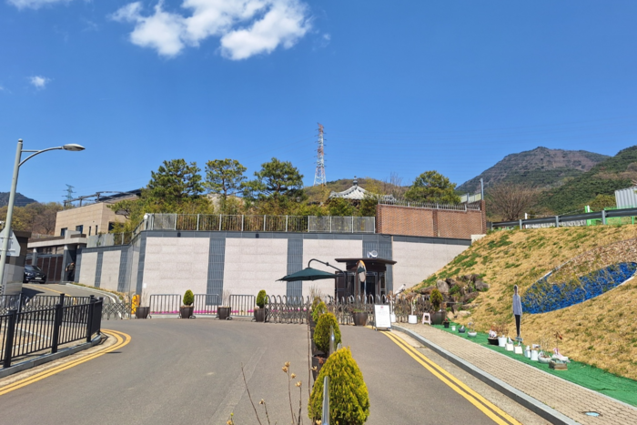 윤석열 대통령이 탄핵 된 이후 첫 일요일(6일)이었지만, 사저 주변은 평소와 다름없는 조용한 분위기를 유지했다. 입구 앞 도로는 한산했으며, 방문객들의 흔적은 곳곳에 놓인 화분과 안내판 정도였다. 비슬산 자락에 자리한 사저는 삼엄한 경비 속에서도 정적만이 감돌았다. <강승규 기자>