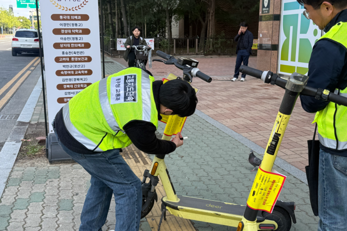 15일 대구 동구 율화광장 인근 보행도로에 무단 방치된 공유형 PM에 단속원이 계고장을 붙이고 있다.
