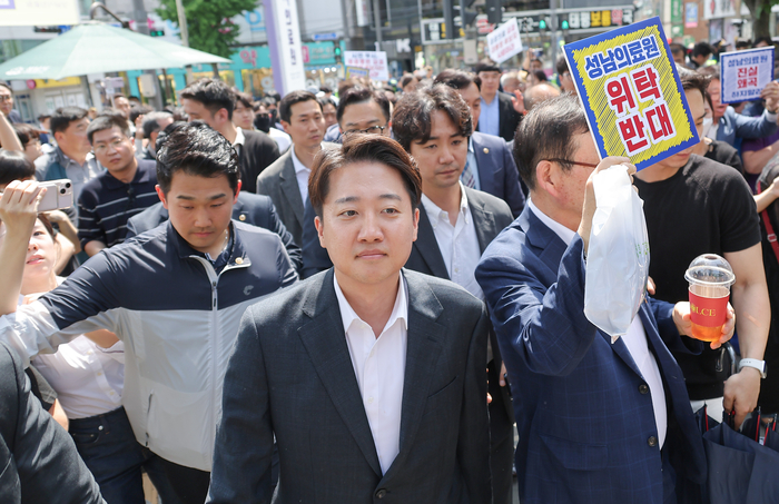 개혁신당 이준석 대선 후보가 지난 21일 경기 성남의료원에 도착, 시민단체 회원들의 항의를 받으며 들어서고 있다.  연합뉴스