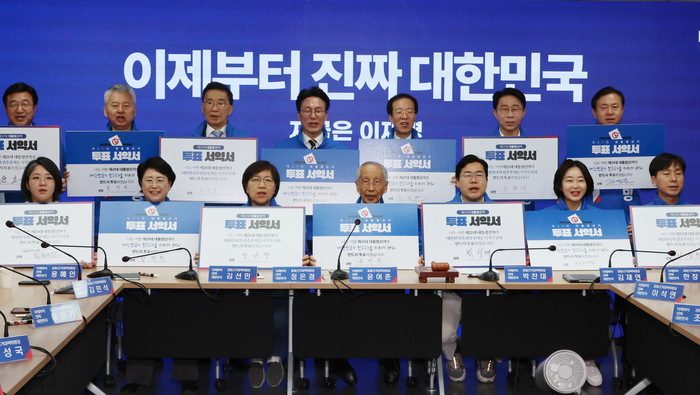 더불어민주당 윤여준·박찬대 상임 총괄선대위원장을 비롯한 공동선대위원장들이 사전투표를 하루 앞둔 28일 서울 여의도 당사에서 열린 중앙선거대책위원회의에서 투표서약서에 서명 후 유권자들에게 투표를 독려하고 있다. 연합뉴스