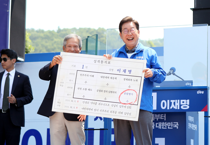 이재명 후보가 1일 안동 유세 현장에서 초등학교 은사인 박병기 선생이 준 '성적표'를 받고 활짝 웃고 있다.<피재윤 기자>