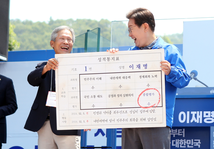 이재명 후보가 1일 안동 유세 현장에서 초등학교 은사인 박병기 선생이 준 '성적표'를 받고 활짝 웃고 있다.<피재윤 기자>