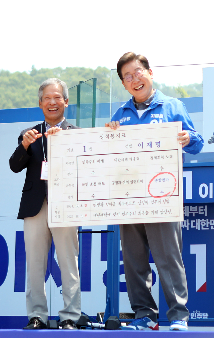 지난 1일 경북 안동 선거 유세에서 당시 이재명 더불어민주당 대선 후보가 1일 초등학교 은사인 박병기 선생이 준 '정치 성적표'를 들고 활짝 웃고 있다.