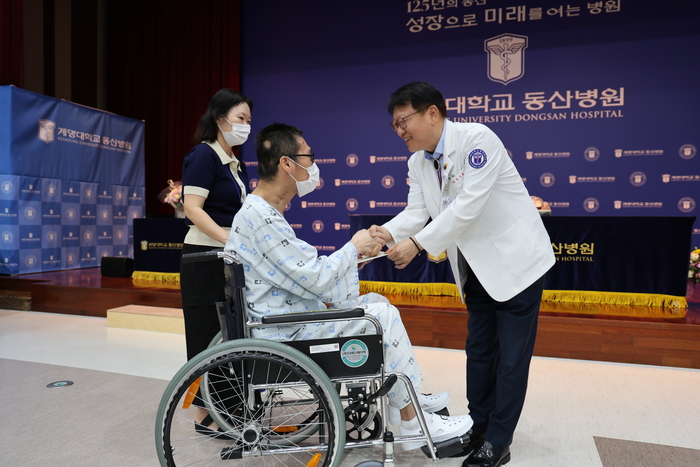 조치흠 동산의료원장이 심장이식 100호 수술 환자에게 건강검진권을 전달하며 빠른 회복과 건강을 기원하고 있다.<동산의료원 제공>