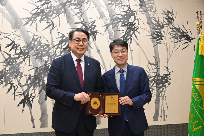 지난 19일 대구시청에서 지역사회 공헌 감사패를 받은 대구한의대 변창훈(왼쪽) 총장이 김정기 대구시장 권한대행과 기념촬영을 하고 있다. <대구한의대 제공>