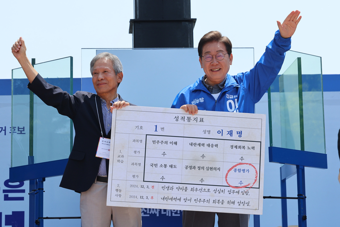 더불어민주당 이재명 대선 후보가 선거를 이틀 앞두고 '험지 공략'에 나선 1일 고향인 경북 안동시의 웅부공원에서 열린 유세에서 이 후보의 초등학교 은사인 박병기 선생님으로부터 대선 후보 모의 성적 통지표를 받고 있다. 연합뉴스