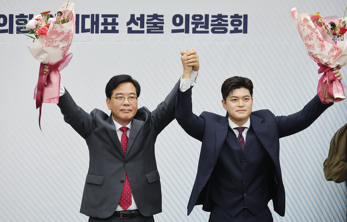 국민의힘 신임 원내대표로 당선된 송언석 의원(왼쪽)이 16일 원내대표 선출 의원총회가 열린 서울 여의도 국회 회의장에서 김용태 비상대책위원장과 손을 잡고 기념촬영하고 있다. 연합뉴스