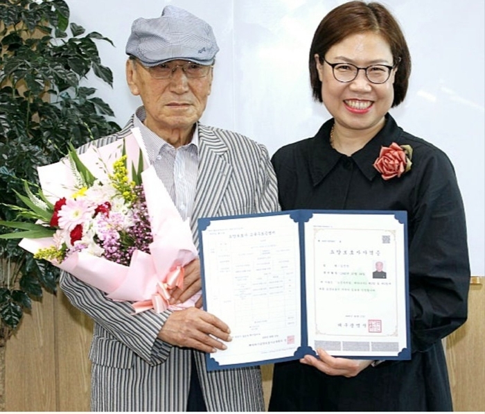 김진만씨가 자신의 요양보호사 자격증을 들고 박선옥 해바라기요양보호사교육원장과 함께 기념촬영을 하고 있다. <김진만씨 제공>