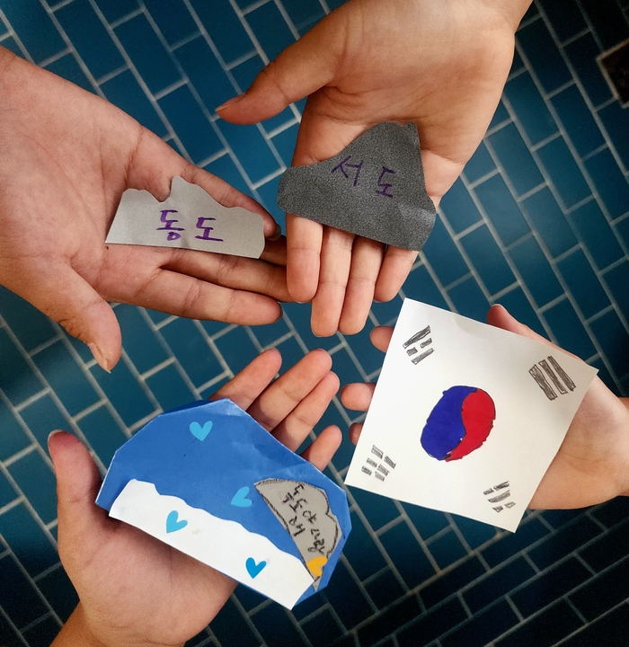 '우리가 만든 손바닥 독도'라는 제목으로 친구들과 함께한 단체 작품. 각자의 손바닥에 동도·서도·파도·태극기를 나눠 그리고 손을 모으면 하나의 독도가 완성되는 협업 퍼포먼스로, 어린이의 단결된 독도 사랑을 상징적으로 표현한 사진.