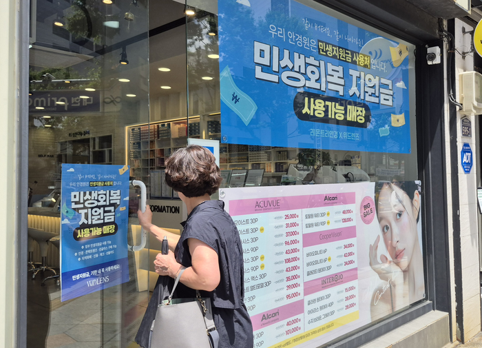 '민생회복 소비쿠폰' 지급 첫 주말인 27일 오후 2시쯤 한 시민이 대구 중구 동성로의 '민생회복 지원금 사용 가능 매장' 안내문이 붙은 안경원으로 들어가고 있다. 조윤화 기자