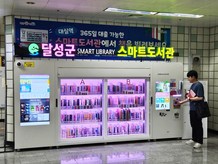 대구도시철도 2호선 대실역 지하 1층 중앙로비에 설치된 '스마트도서관'에서 한 시민이 도서를 대출하고 있다.<달성군 제공>