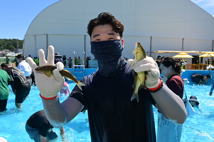 경북 봉화군 내성천 일원에서 열린 제27회 봉화은어축제 맨손잡이 체험장에서 한 참가자가 직접 잡은 은어를 들어 보이고 있다. <봉화군 제공>
