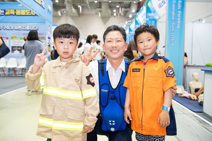 김장호 구미시장이 아이천국 경북 구미 페스티벌에 참여한 구미소방서 체험부스에서 하임리히법 안전교육 실습 조끼를 입고 아이들과 기념사진 촬영을 하고 있다. <구미시 제공>