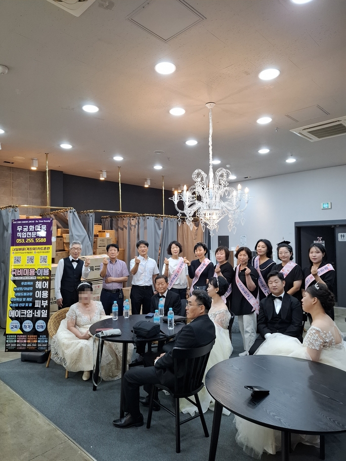 단장을 마친 신랑·신부 여섯 쌍과 여준현 원장(뒷줄 왼쪽에서 셋째) 및 봉사자들이 함께 웃으며 기념사진을 찍고 있다. <무궁화미용직업전문학교 제공>