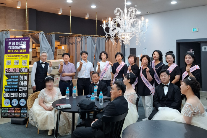 단장을 마친 신랑·신부 여섯 쌍과 여준현 원장(뒷줄 왼쪽에서 셋째) 및 봉사자들이 함께 웃으며 기념사진을 찍고 있다. <무궁화미용직업전문학교 제공>