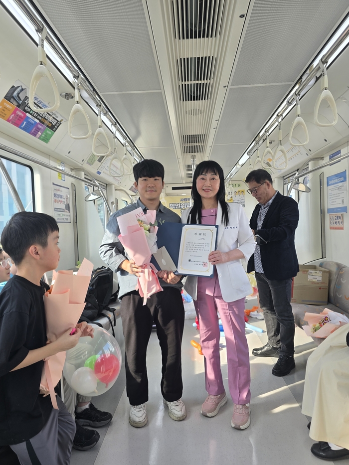 박언휘 박사(오른쪽)가 지난 1일 대구도시철도 3호선 열차 안에서 장애 학생들에게 장학증서를 전달한 뒤 기념촬영을 하고 있다.<박언휘 슈바이처재단 제공>