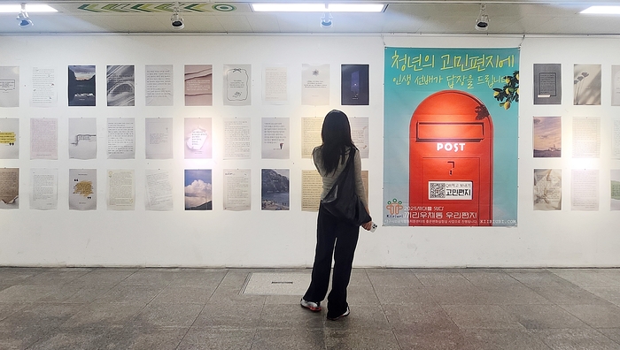 대구도시철도 2호선 범어역 대구아트웨이에 전시된 고민편지를 한 청년이 유심히 읽고 있다.
