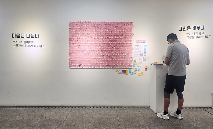 한 시민이 대구도시철도 2호선 범어역 대구아트웨이에 전시된 고민편지를 읽고 난 뒤 소감을 남기고 있다.
