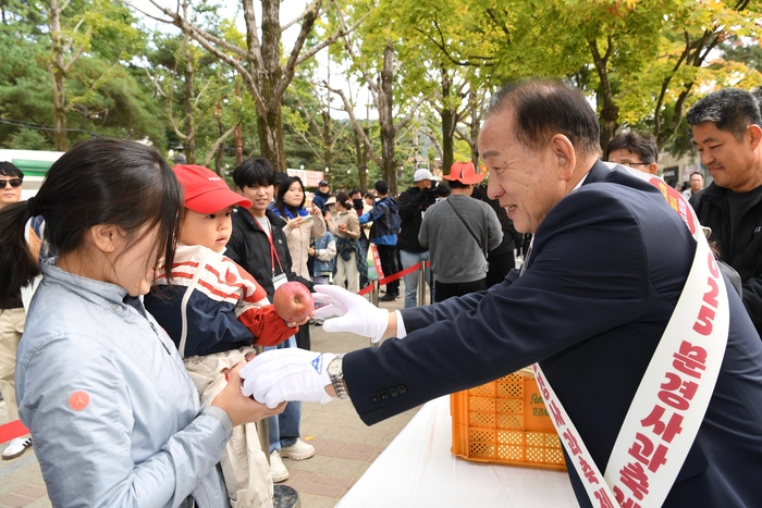 신현국 문경시장(오른쪽)이 2025 문경사과축제장을 찾은 관광객들에게 문경사과를 나눠주며 문경사과축제와 문경사과를 홍보하고 있다. <문경시제공>