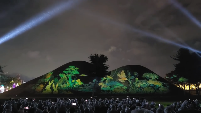 경주 대릉원 고분군을 배경으로 펼쳐진 2025 국가유산 미디어아트 경주 대릉원 공연 장면. 미디어파사드와 조명이 어우러져 토끼와 소나무, 새 그림 등이 고분 표면 위에 투사되고 있다. 경주시 제공