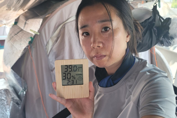 박정혜 금속노조 한국옵티칼하이테크지회 부지회장이 올해 여름 옥상에서 고공농성 중 온도계를 들어보이고 있다. 텐트 안 온도는 39℃이지만 옥상 바닥 온도는 50℃가 넘는다. <박정혜씨 제공>