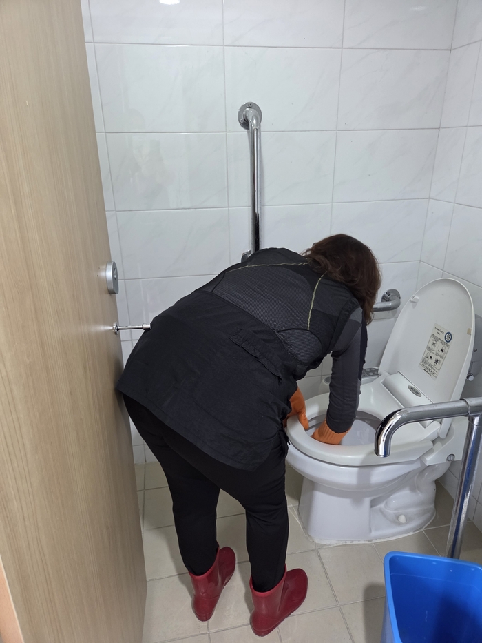 기숙사 내 화장실 양변기에 손을 넣어 오염물을 지우는 한 여성청소노동자.<익명을 요구한 여성청소노동자 제공>