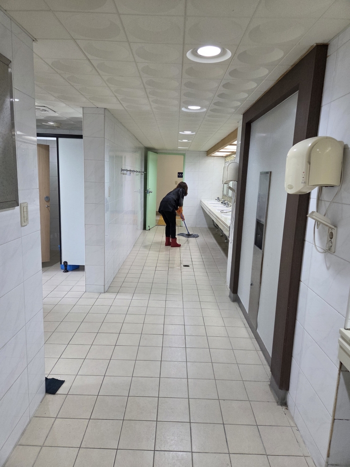한 여성청소노동자가 대학 기숙사 내 화장실 바닥을 밀대로 청소하고 있다.<익명을 요구한 여성청소노동자 제공>