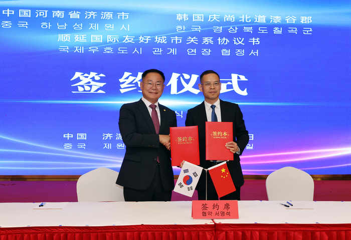 김재욱 칠곡군수(왼쪽)와 친바오젠(秦保振) 제원시장이 국제우호도시 협약서에 서명하고 기념촬영을 하고 있다.<칠곡군 제공>