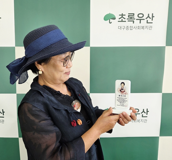 신희숙씨가 어머니 고(故) 채고례 여사의 이름과 얼굴이 담긴 헌액패를 들고 기념촬영을 하고 있다. <신희숙씨 제공>