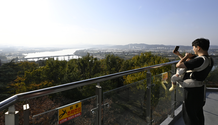 화원유원지 상화대 전망대에서 한 시민이 아이를 안고 낙동강을 배경으로 사진을 찍고 있다. 전망대에 오르면 낙동강 본류와 금호강이 한눈에 합쳐지고, 멀리 강정보와 대구 도심이 시원하게 펼쳐진다. 가족 단위 방문객들이 가장 많이 찾는 포토 명소이자 휴식 공간이다.이윤호 기자 yoonhohi@yeongnam.com
