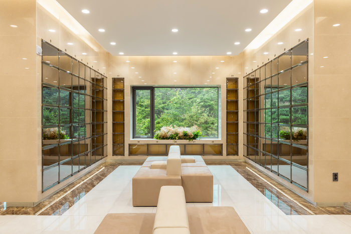 경북 성주 우성공원묘원의 실내 봉안공간. 밝은 베이지 톤과 자연 채광을 활용한 현대적 인테리어가 특징으로, 중앙 창 너머의 숲 전망이 고요한 추모 분위기를 조성한다.<우성공원묘원 제공>