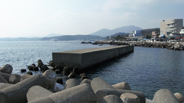 옹벽 너머 바다 가운데 놓여 있는 사각형 콘크리트 더미는 타이셀 공법이라는 해양신기술이 적용된 회파블록 방파제다. 월파량을 10분의 1이하로 떨어뜨린다.