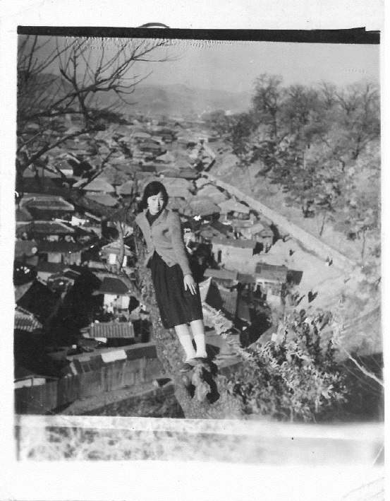 1950년대 대구 복현동 피란민촌 전경. 언덕 위에 앉은 한 여성 뒤로 마을의 모습이 펼쳐져 있다. 북구청 제공