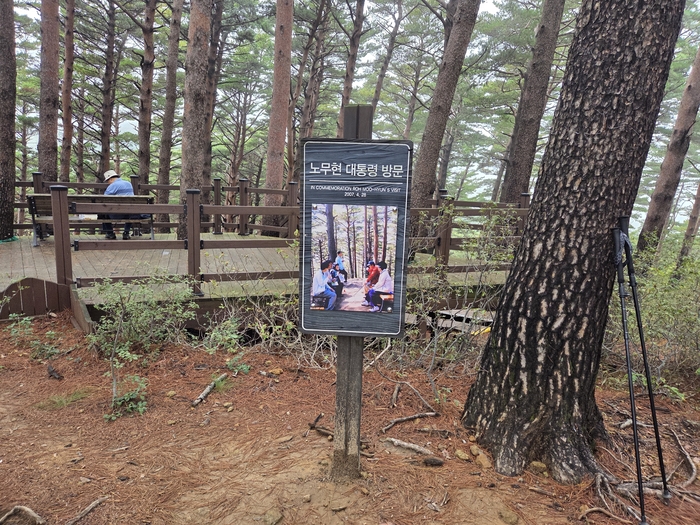 노무현 대통령 방문 사진과 쉼터. 고(故) 노무현 대통령과 권양숙 여사가 다정하게 벤치에 앉아 쉬는 사진이 담긴 안내판이 세워져 있다.