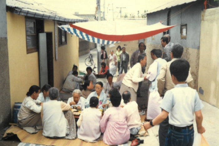 1970년대 대구 북구 복현1동 골목에서 주민들이 돗자리를 펴고 함께 마을 잔치를 즐기고 있다. <북구청 제공>