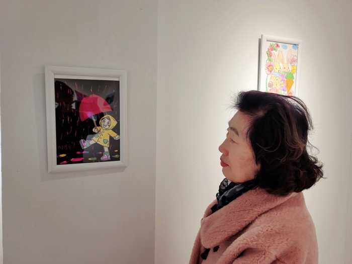 엄마의 손끝이 남긴 풍경 앞에서, 큰딸 권영애 씨가 조용히 작품 감상을 하고 있다. 김동 시민기자