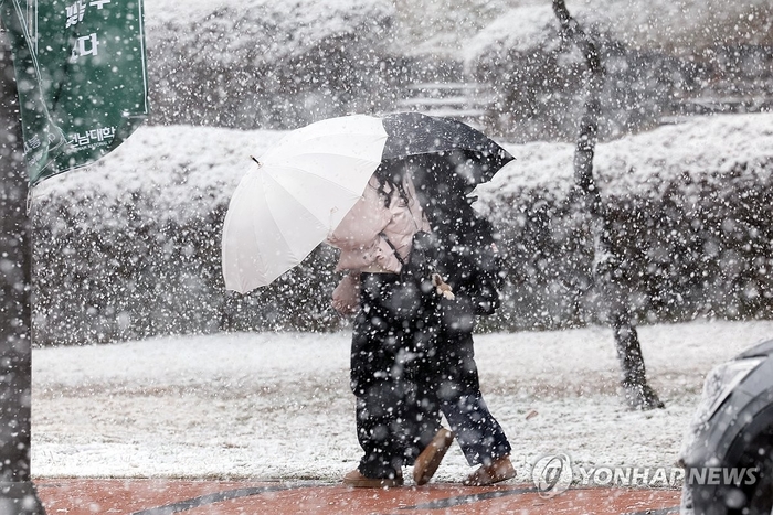 우산으로 막는 눈보라 <연합뉴스>