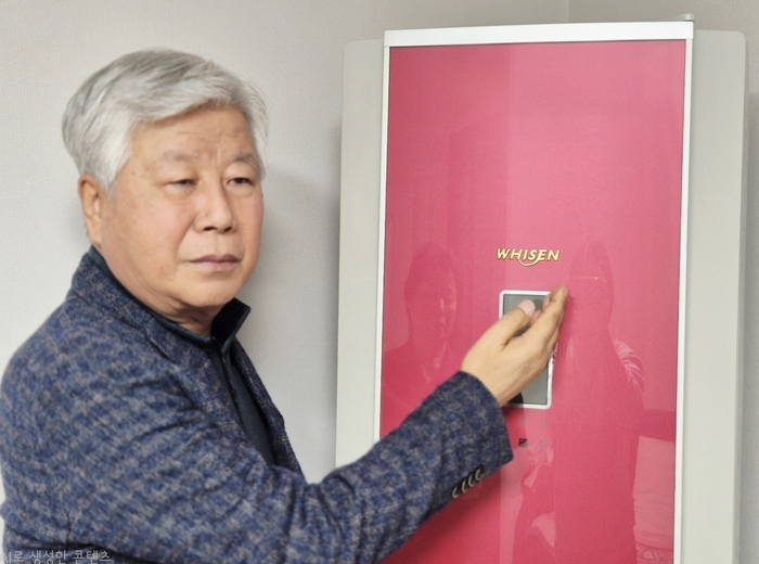 김기조씨가 2005년부터 사용 중인 휘센 에어컨의 순금 로고를 가리키고 있다. <김기조씨 제공>