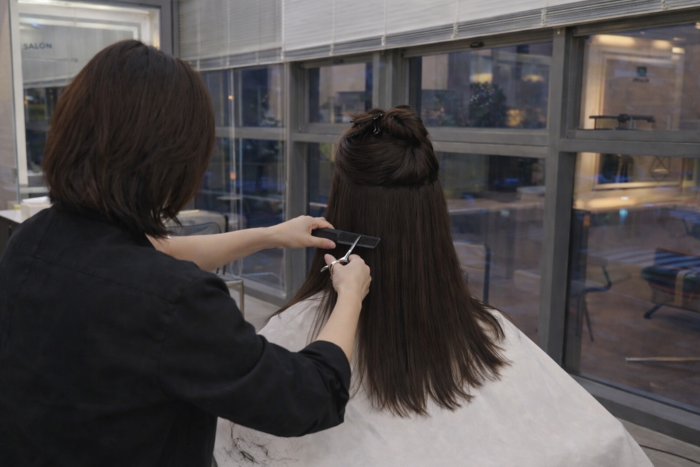 보조 미용사가 고객의 머리를 정리하고 있다. 샴푸와 염색, 드라이 준비 등 눈에 잘 띄지 않는 손길들이 쌓여 미용실의 하루가 완성된다. <보조미용사 박모씨 제공>