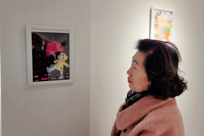 엄마의 손끝이 남긴 풍경 앞에서, 큰딸 권영애 씨가 조용히 작품 감상을 하고 있다. 김동 시민기자