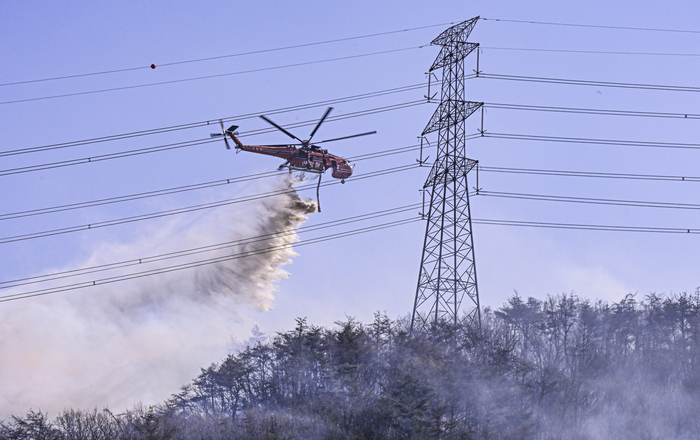 8일 경북 경주시 문무대왕면 입천리 산불 현장에서 진화헬기가 송전탑과 전선을 아슬아슬하게 피해 불길 위로 물을 뿌리고 있다. 강풍과 송전선로가 겹치며 공중 진화에 제약이 컸다.
이현덕기자 lhd@yeongnam.com
