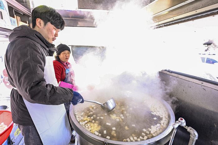 12일 대구 달서구 두류공원에서 운영된 무료급식소 사랑해밥차 현장에서 최시웅 기자가 배식을 앞두고 대형 가마솥에 끓고 있는 떡국 국물을 조리하고 있다.
이현덕기자 lhd@yeongnam.com