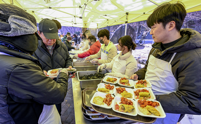 12일 대구 달서구 두류공원에서 운영된 무료급식소 사랑해밥차 현장에서 최시웅 기자를 비롯한 자원봉사자들이 취약계층에게 떡국과 반찬을 배식하고 있다.
이현덕기자 lhd@yeongnam.com