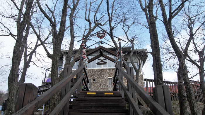 사랑터널. 녹슨 자물쇠와 빛바랜 쪽지들이 주렁주렁 걸려 있다. 건물은 케이블카 상부 정류장으로 2층은 식당이다.