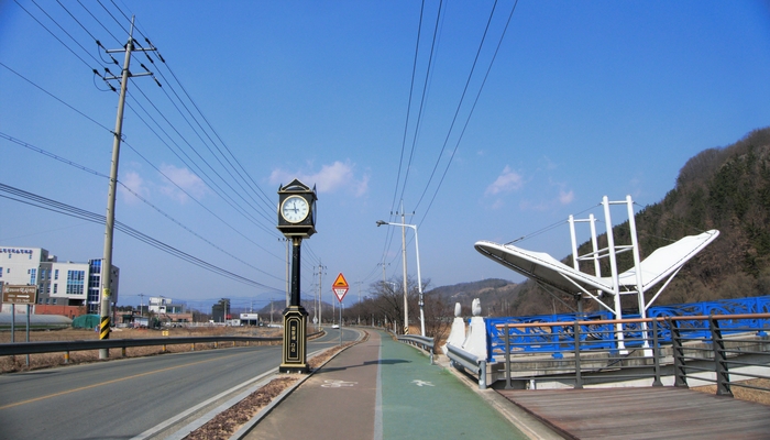 인도교인 파랑새 다리와 시계탑. 다리 앞에 덕사 이정표가 있다. 봄이 되면 파랑새다리 주변은 온통 유채꽃 밭이 된다.