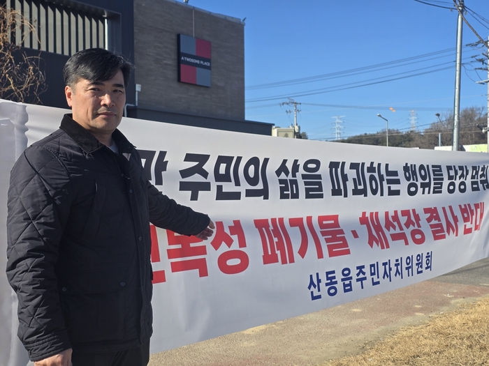 최광재 산동읍단체장협의회장이 주민들이 내건 현수막 앞에서 산동읍 일대에 추진 중인 지정산업폐기물처리시설과 초대형 채석장 반대 이유를 설명하고 있다. <박용기 기자>